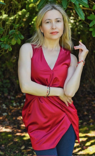 Creative portrait — woman in red silk top among lush greenery